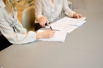 two woman signing compliance documents